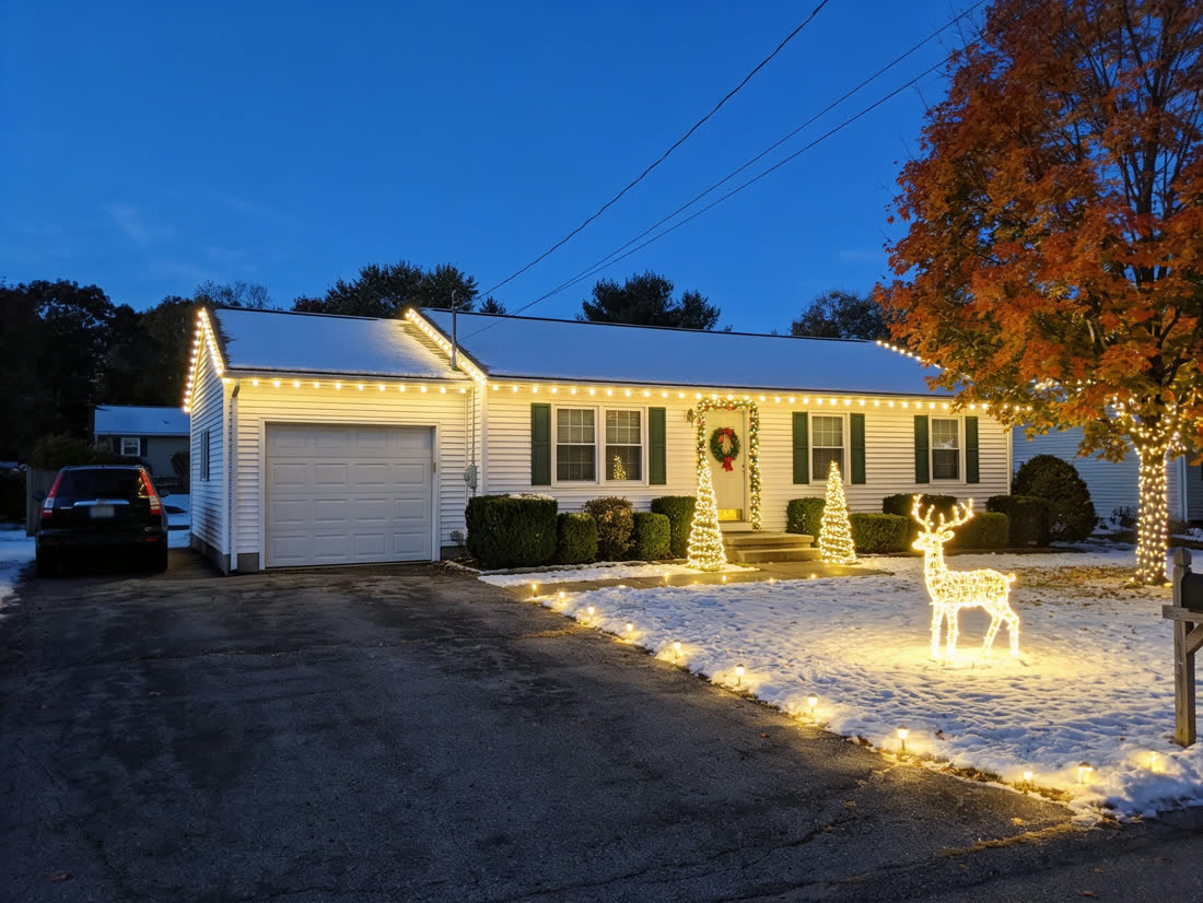 The same house shown with warm white roofline lighting at dusk
